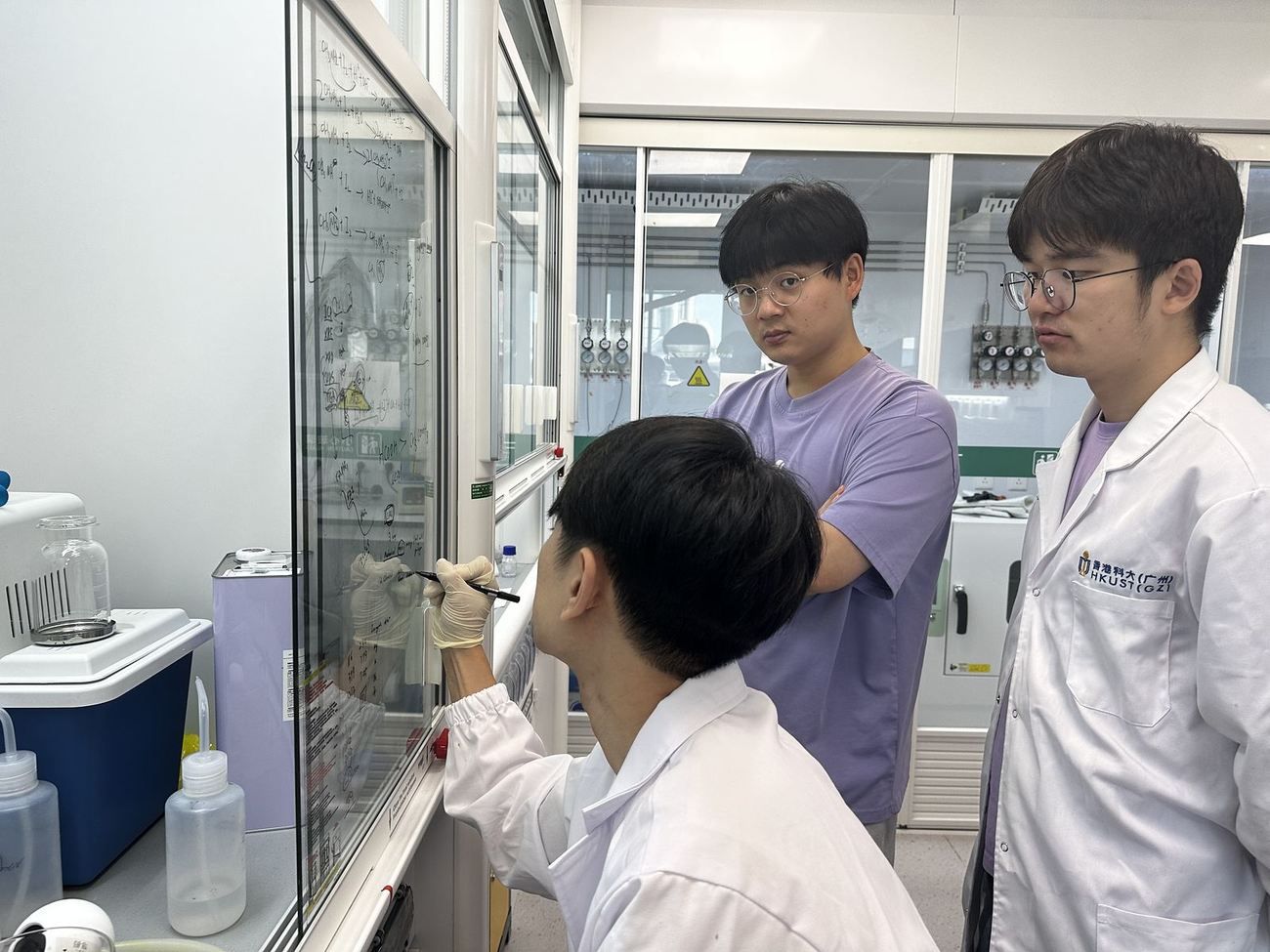 Group members discussing beside a glovebox in the laboratory